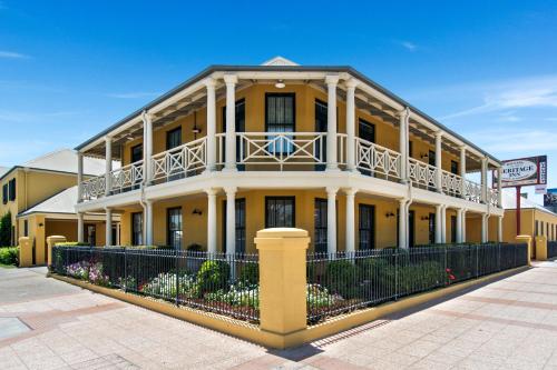 a large yellow building with a balcony on a street at Ballina Heritage Inn in Ballina
