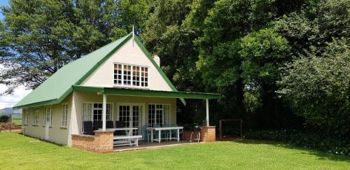 a small house with a green roof on a field at Pennygum Country Cottages in Underberg