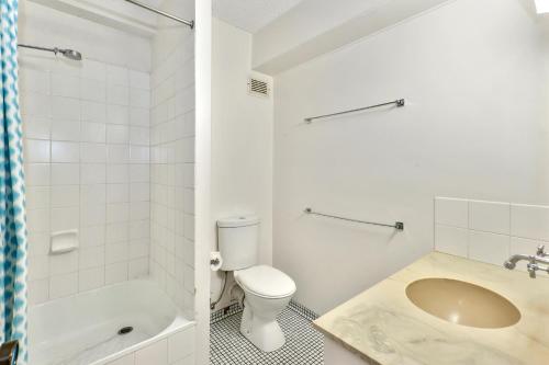 a white bathroom with a toilet and a sink at Warroo Apartments in Alexandra Headland