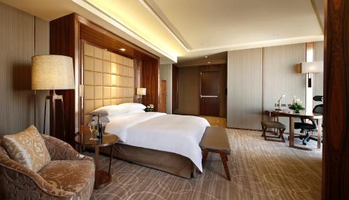 a hotel room with a large bed and a chair at Crowne Plaza Kunming City Centre by IHG in Kunming