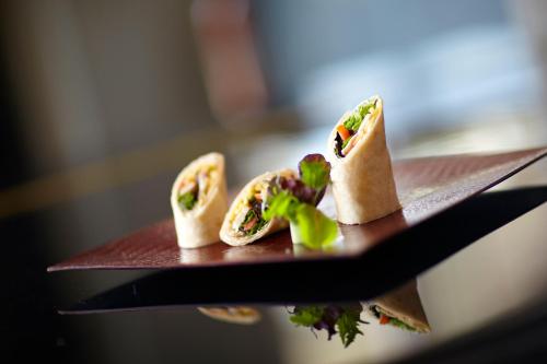 three hot dogs on a plate on a table at Crowne Plaza Limassol by IHG in Limassol
