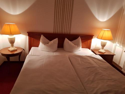 a bedroom with a large white bed with two lamps at Hotel zum Mückenberger Hof in Lauchhammer