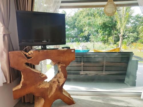 a tv on top of a wooden stand next to a window at In Touch Resort in Ko Tao