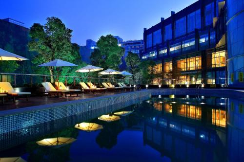 a pool with chairs and umbrellas next to a building at Crowne Plaza Taizhou, an IHG Hotel in Taizhou