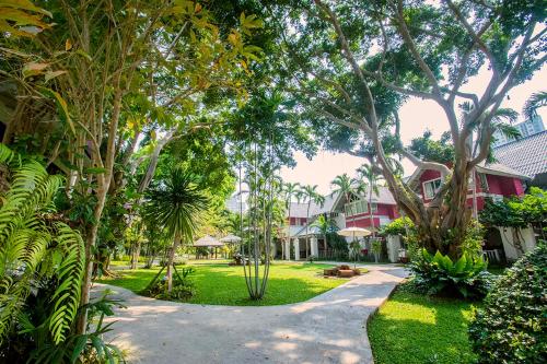 einen Gehweg durch einen Garten mit Bäumen und einem Gebäude in der Unterkunft Natural Park Resort Pattaya in Jomtien Beach