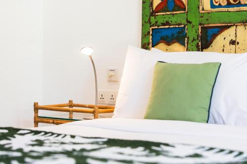 a bed with white sheets and a green pillow at Villa Atma in Seminyak