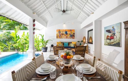 a dining room with a table and a swimming pool at Villa Atma in Seminyak