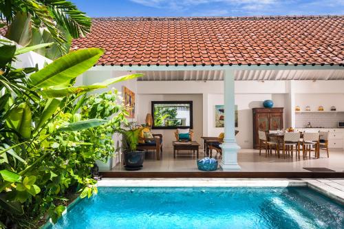 a villa with a swimming pool in front of a house at Villa Atma in Seminyak