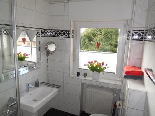 ein Bad mit einem Waschbecken, einem WC und einem Fenster in der Unterkunft Ferienwohnung Eulenturm in Xanten