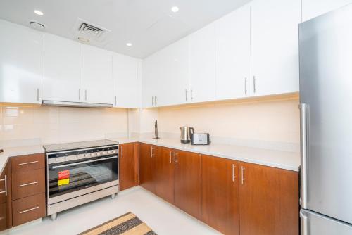 a kitchen with white appliances and wooden cabinets at Fantastay Spacious 3 BDR plus maids with Burj Khalifa View in Dubai