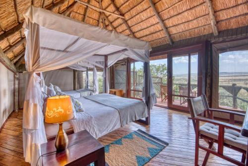 ein Schlafzimmer mit einem Bett und einem Tisch mit einer Lampe in der Unterkunft Mbali Mbali Soroi Serengeti Lodge in Banagi