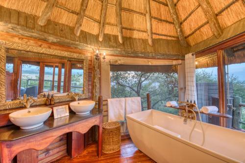 
a bathroom with a large tub and a large window at Mbali Mbali Soroi Serengeti Lodge in Banagi
