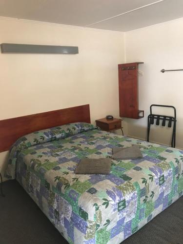 ein Schlafzimmer mit einem Bett mit einer Decke darauf in der Unterkunft Blackall Coolibah Motel in Blackall