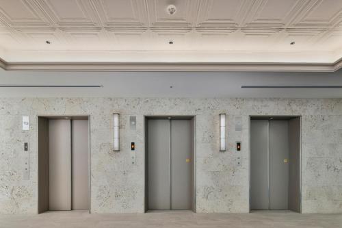 a row of elevator doors in a room with marble walls at Lequ Okinawa Chatan Spa ＆ Resort in Chatan
