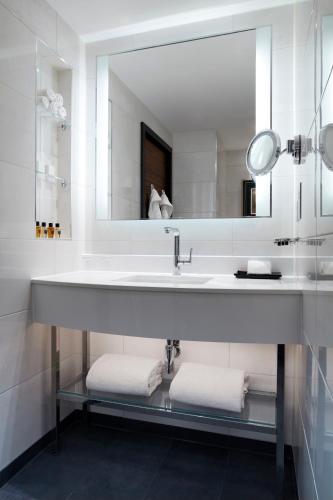 a bathroom with a sink with a mirror and towels at Hyatt Regency London Albert Embankment in London
