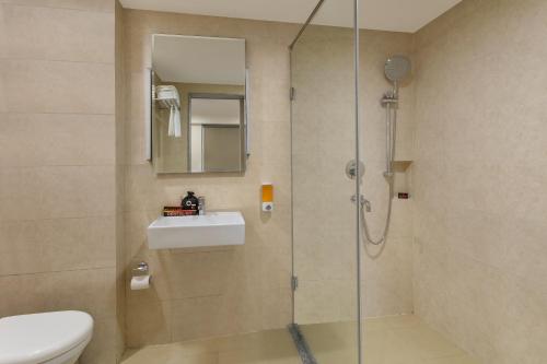 a bathroom with a shower with a sink and a toilet at GINGER Noida City Center in Noida