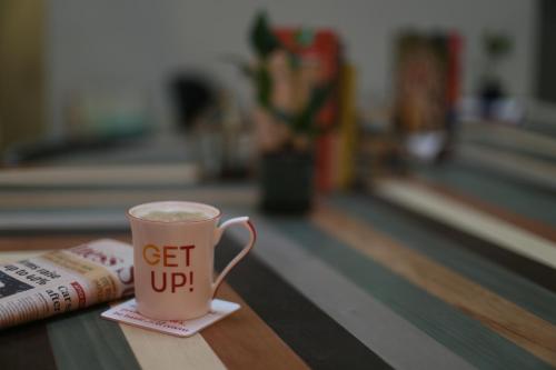 a cup of coffee sitting on a table next to a newspaper at Ginger Patna in Patna