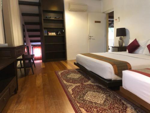 a bedroom with two beds and a table and a desk at Spices Hotel in George Town