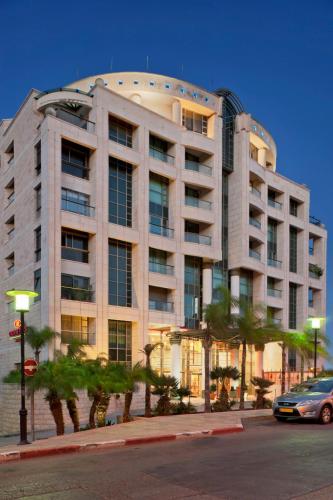 a large building with palm trees in front of it at Crowne Plaza Haifa by IHG in Haifa
