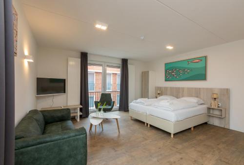 ein Hotelzimmer mit einem Bett und einem Sofa in der Unterkunft ApartHotel Zoutelande in Zoutelande