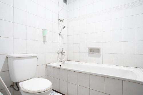 a white bathroom with a toilet and a bath tub at Hotel Bandung Permai in Bandung