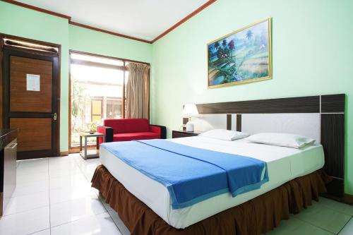 a bedroom with a large bed and a red chair at Hotel Bandung Permai in Bandung