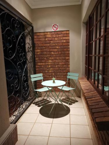 a table and chairs on a balcony with a brick wall at Klyne Jiweel Guesthouse in Pretoria
