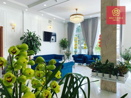 ein Wohnzimmer mit blauen Sofas und Pflanzen in der Unterkunft Bảo Thịnh 2 Hotel in Da Lat