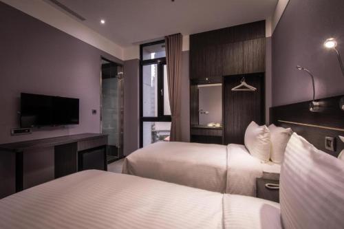 台北市にあるイースー ホテル タイペイ ニンシアのベッド2台とテレビが備わるホテルルームです。