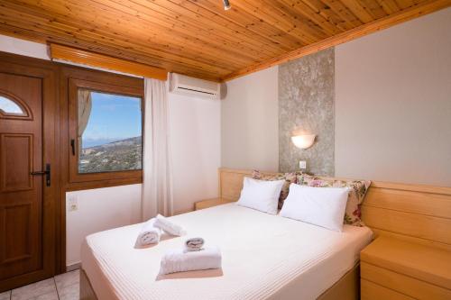 1 dormitorio con 1 cama con sábanas blancas y ventana en Archodissa Pansion, en Alyki