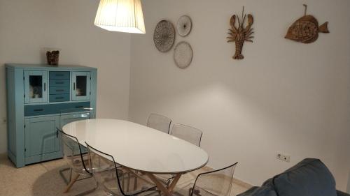 una cocina con una mesa y sillas blancas y un armario azul en Apartamento Julieta, en Sanlúcar de Barrameda