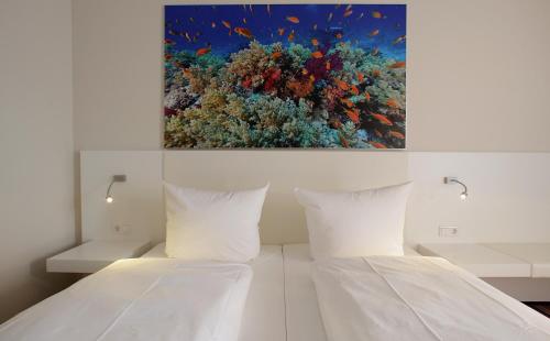 a bedroom with a white bed with a painting on the wall at Friendly Cityhotel Oktopus in Siegburg