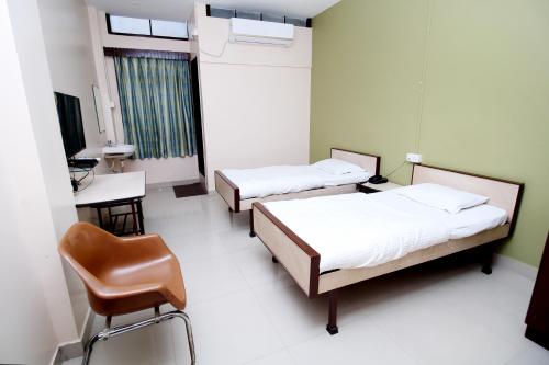 a hospital room with two beds and a chair at Hotel Gomatgiri in Aurangabad