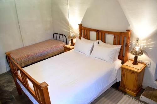 a bedroom with a large white bed and two lamps at Die Ou Huis Accommodation in Ashton