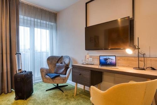 a hotel room with a desk with a laptop and a chair at Vienna House Easy by Wyndham Ingolstadt in Ingolstadt