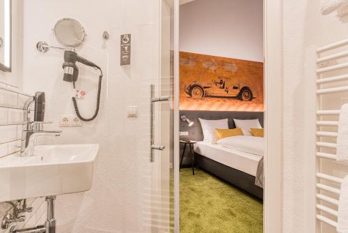 a bathroom with a sink and a bedroom with a bed at Vienna House Easy by Wyndham Ingolstadt in Ingolstadt