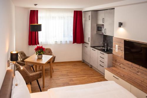a room with a bed and a kitchen with a table at Appartementhaus AURUM - Summercard included in Zell am See