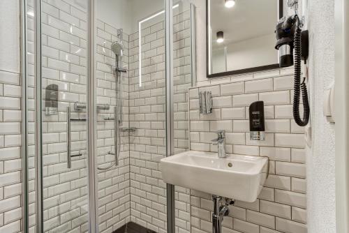 a white bathroom with a sink and a shower at Vienna House Easy by Wyndham Ingolstadt in Ingolstadt