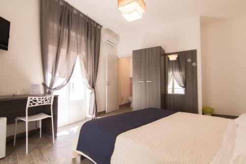 Schlafzimmer mit einem Bett, einem Schreibtisch und einem Fenster in der Unterkunft Cavour Rooms in Syrakus