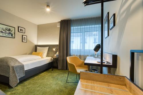 Habitación de hotel con cama y escritorio en NYCE Hotel Ingolstadt, en Ingolstadt