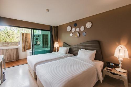 two beds in a hotel room with two lamps at Rachabhura Hotel in Ratchaburi