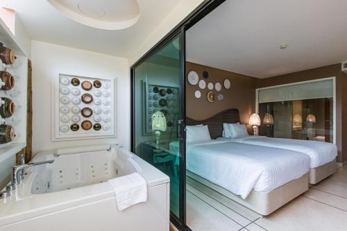 a bedroom with a large bed and a bath tub at Rachabhura Hotel in Ratchaburi