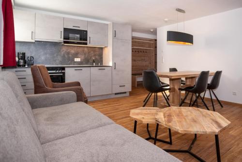 a living room with a table and chairs and a kitchen at Appartementhaus AURUM - Summercard included in Zell am See
