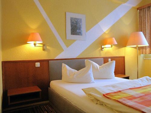 a hotel room with two beds and two lamps at Hotel Stadt Wittstock in Wittstock