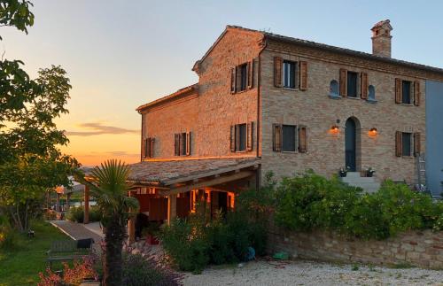 an old brick building with a sunset in the background at Agriturismo Unico Senso - Glamping in Montottone
