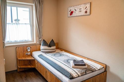 - un petit lit dans une chambre avec fenêtre dans l'établissement Pension Sengmüller, à Buchbach