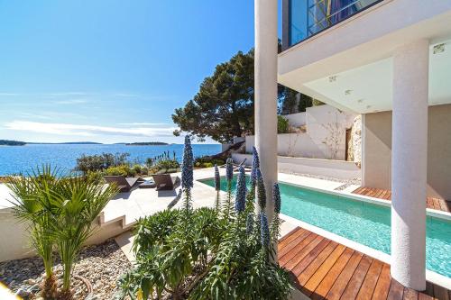 a house with a swimming pool next to the water at Golden Rays Luxury Villas & Apartments in Primošten