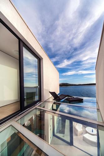 a glass balcony with a view of the water at Golden Rays Luxury Villas & Apartments in Primošten