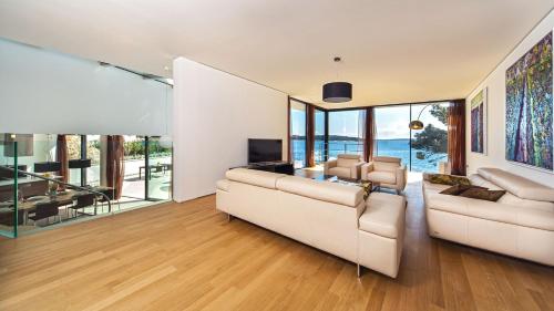 a living room with two white couches and glass walls at Golden Rays Luxury Villas & Apartments in Primošten