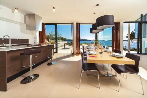 a kitchen with a long wooden table and black chairs at Golden Rays Luxury Villas & Apartments in Primošten